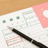 婚姻届の『同居を始めたとき』欄に黒いペンが置かれ、隣にはピンクのハート入り封筒が添えられている様子
