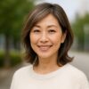 若々しい印象のヘアカラーと明るい表情が魅力的な50代の日本人女性が屋外で笑顔を見せる様子
