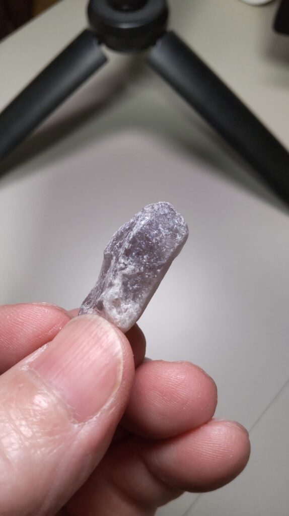 歯ブラシで清掃する前のポイント状アメジスト原石。紫色の表面に白っぽい斑点状の部分が見える