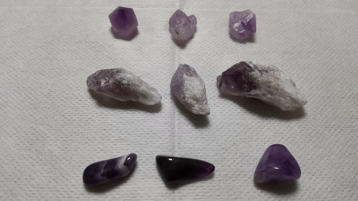 アメジストとは?紫水晶の特徴・硬度・成分を鉱物学から解説 小さなアメジスト原石、細長いポイント状原石、磨かれたさざれ石を3個ずつ3段に並べた比較