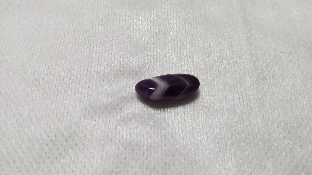 細長い紫色のさざれ石の裏側に見えるV字状の白い帯模様